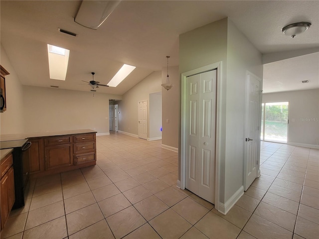 kitchen featuring light tile patterned flooring, vaulted ceiling with skylight, black range with electric stovetop, and baseboards