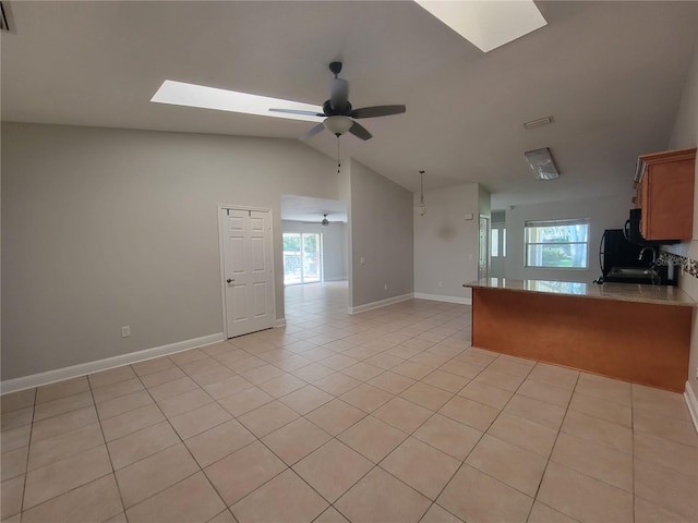 kitchen with light tile patterned floors, a peninsula, a healthy amount of sunlight, and open floor plan