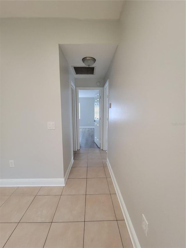 hall featuring light tile patterned flooring, visible vents, and baseboards