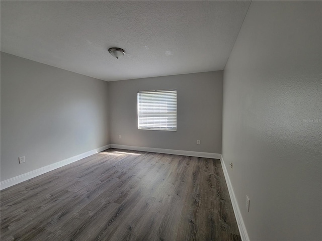 spare room featuring baseboards, a textured ceiling, and wood finished floors