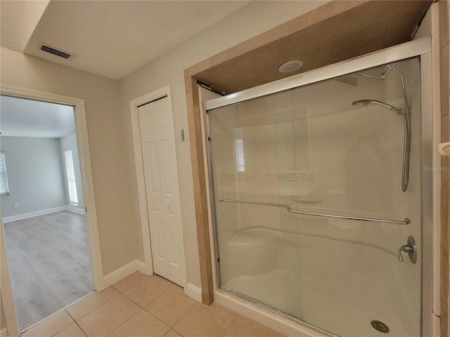 bathroom with tile patterned flooring, visible vents, a stall shower, and baseboards