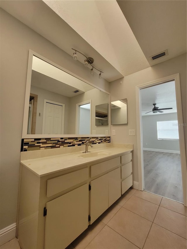 bathroom featuring vanity, visible vents, baseboards, decorative backsplash, and tile patterned floors