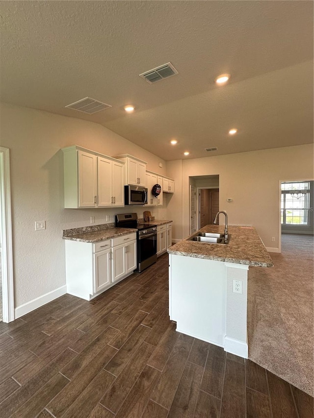 kitchen with appliances with stainless steel finishes, white cabinetry, sink, dark hardwood / wood-style flooring, and a kitchen island with sink