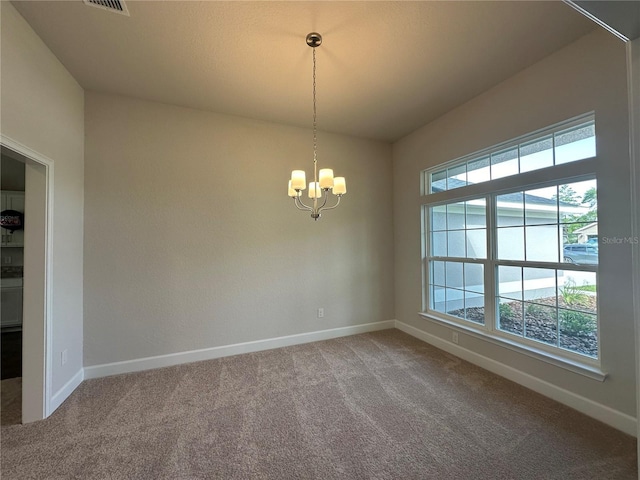 carpeted empty room with a chandelier