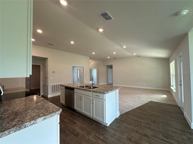 kitchen with sink, dishwasher, white cabinetry, light stone counters, and an island with sink