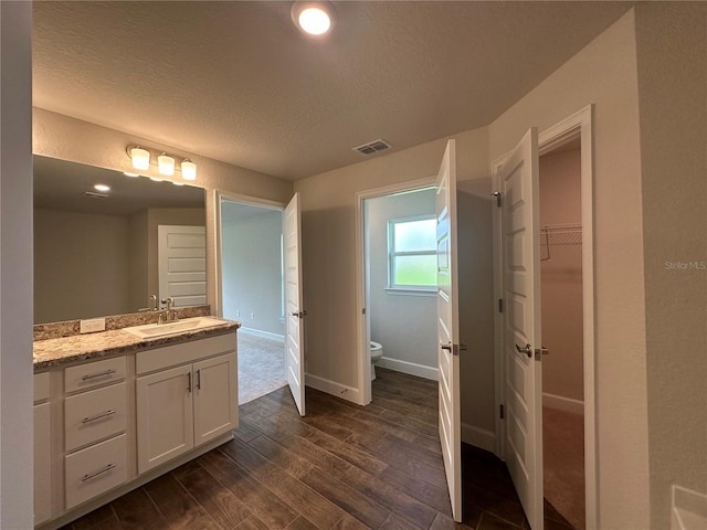 bathroom with vanity, a textured ceiling, wood-type flooring, and toilet