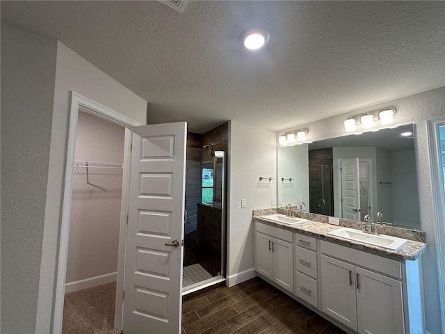 bathroom featuring vanity, a shower with shower door, and a textured ceiling