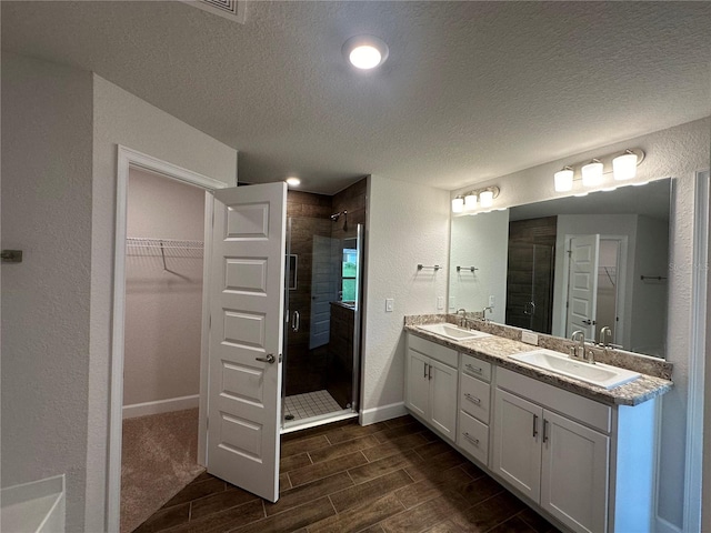 bathroom featuring vanity, a textured ceiling, and walk in shower