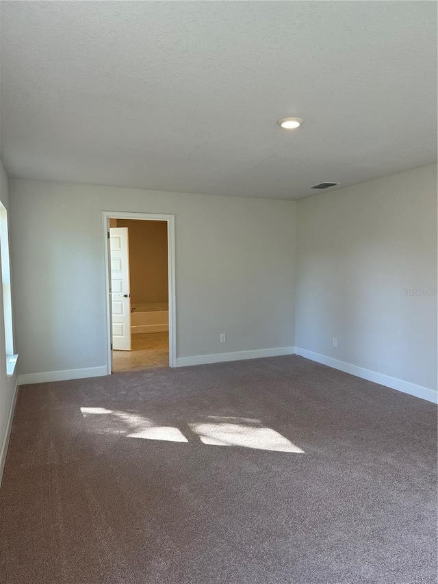 spare room featuring carpet floors and a textured ceiling