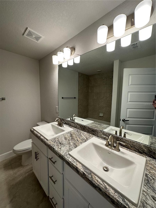 bathroom with vanity, toilet, and a textured ceiling