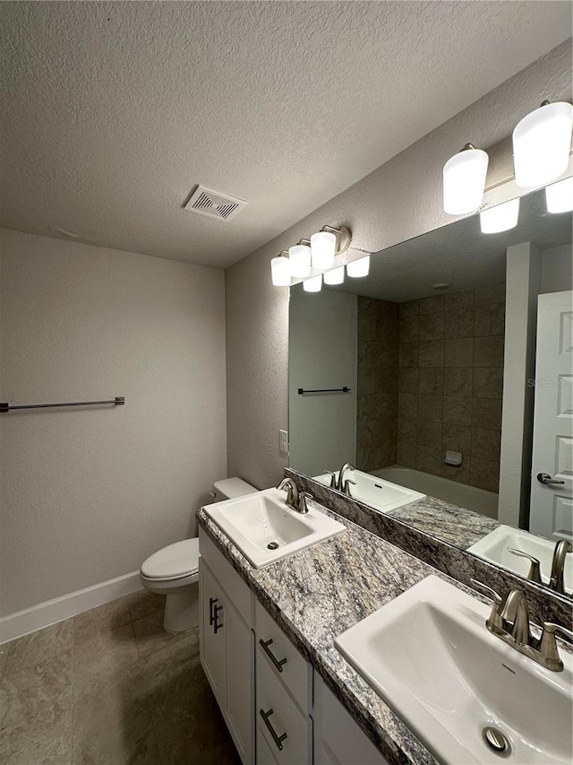 bathroom featuring a bathing tub, vanity, toilet, tile patterned floors, and a textured ceiling