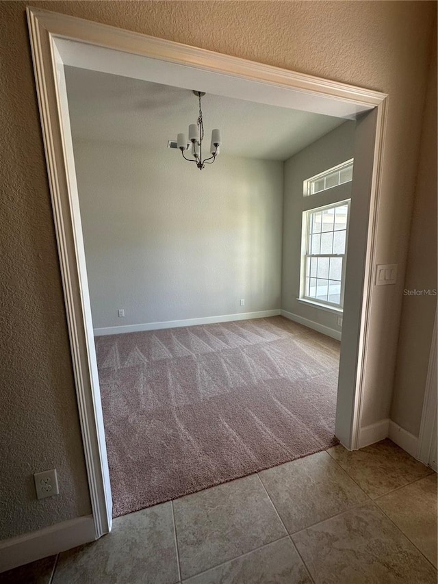 unfurnished dining area featuring a chandelier and carpet flooring