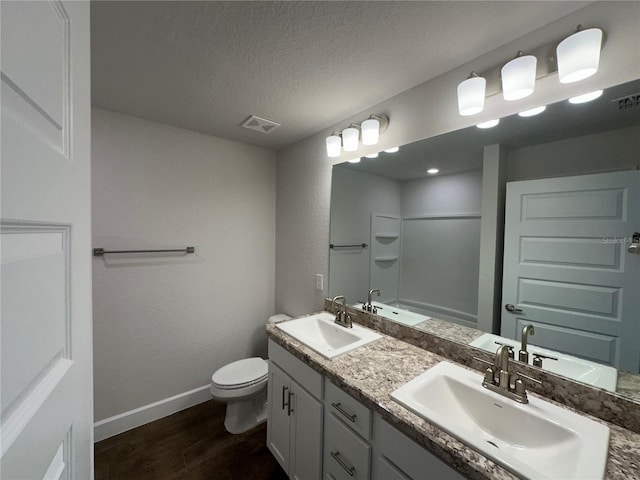 full bathroom with toilet, wood-type flooring,  shower combination, a textured ceiling, and vanity