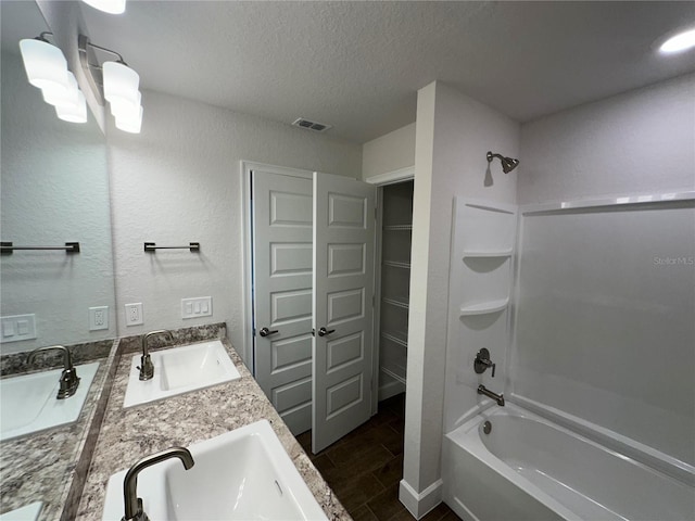 bathroom featuring vanity, bathtub / shower combination, and a textured ceiling