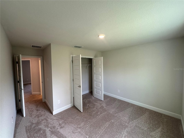 unfurnished bedroom featuring light colored carpet, a textured ceiling, and a closet