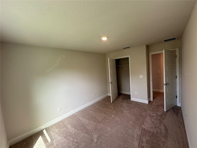 unfurnished bedroom with carpet, a textured ceiling, and a closet