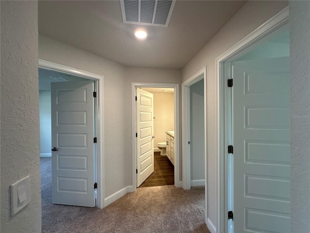 hall with dark colored carpet