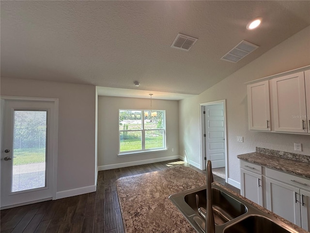 kitchen with lofted ceiling, sink, decorative light fixtures, dark hardwood / wood-style flooring, and white cabinets