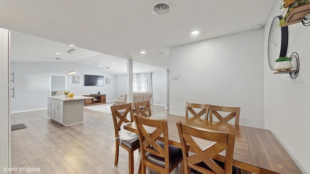 dining area with vaulted ceiling and light hardwood / wood-style floors