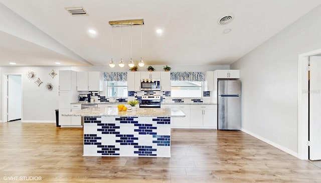 kitchen featuring decorative light fixtures, a center island, white cabinets, and appliances with stainless steel finishes