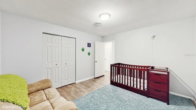 bedroom featuring a closet, a textured ceiling, and light hardwood / wood-style flooring