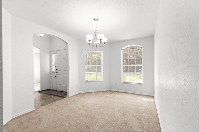 interior space featuring an inviting chandelier, carpet floors, and a textured ceiling