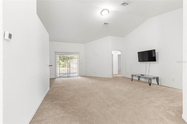 unfurnished living room featuring vaulted ceiling and light colored carpet