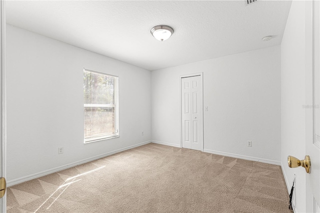 carpeted empty room featuring a textured ceiling