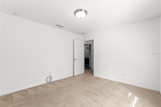 empty room featuring light carpet and a textured ceiling