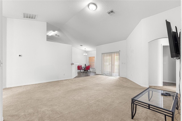 interior space featuring light colored carpet, vaulted ceiling, a textured ceiling, and a notable chandelier