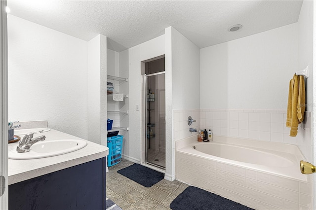 bathroom with tile patterned flooring, vanity, separate shower and tub, and a textured ceiling