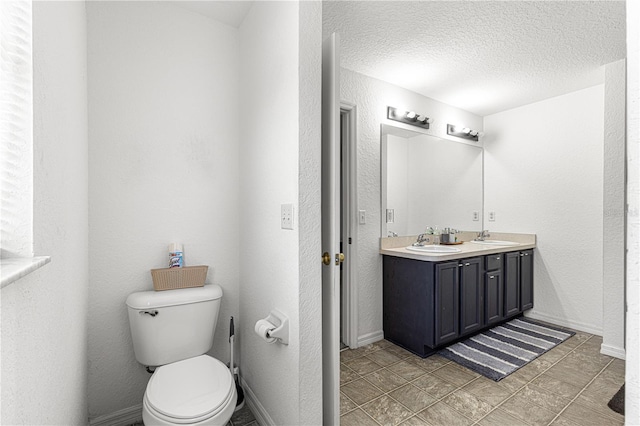 bathroom with vanity, toilet, and a textured ceiling