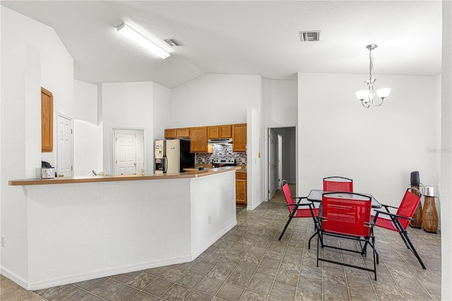 kitchen featuring backsplash, stainless steel appliances, a notable chandelier, decorative light fixtures, and vaulted ceiling