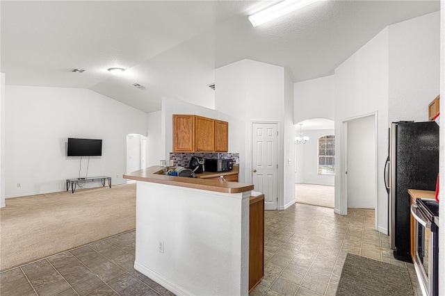 kitchen with lofted ceiling, carpet flooring, stainless steel range with electric cooktop, kitchen peninsula, and an inviting chandelier