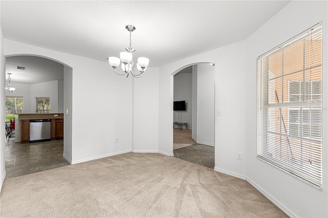 unfurnished room featuring a chandelier, carpet floors, and a textured ceiling