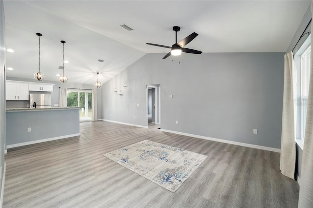 unfurnished living room featuring ceiling fan, light hardwood / wood-style floors, and lofted ceiling