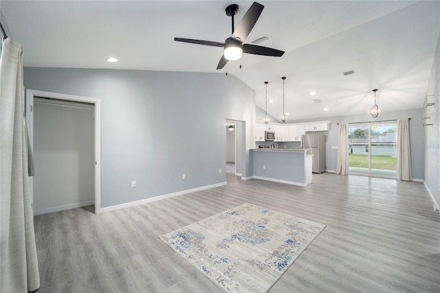 unfurnished living room with lofted ceiling, light hardwood / wood-style floors, and ceiling fan with notable chandelier