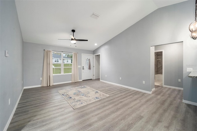 interior space featuring ceiling fan with notable chandelier, light hardwood / wood-style floors, and vaulted ceiling