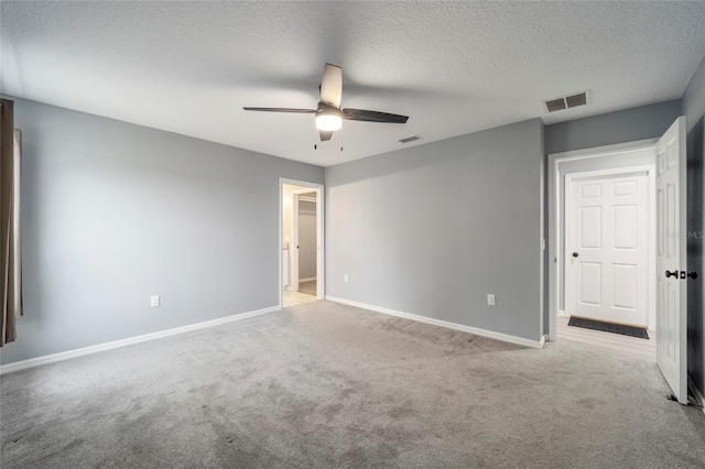 carpeted spare room featuring ceiling fan and a textured ceiling