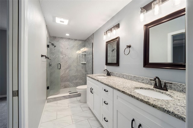 bathroom featuring vanity, a shower with shower door, and toilet