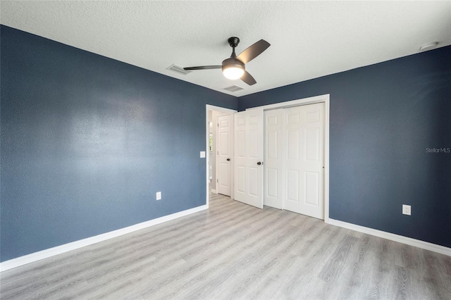 unfurnished bedroom with ceiling fan, light hardwood / wood-style flooring, a textured ceiling, and a closet