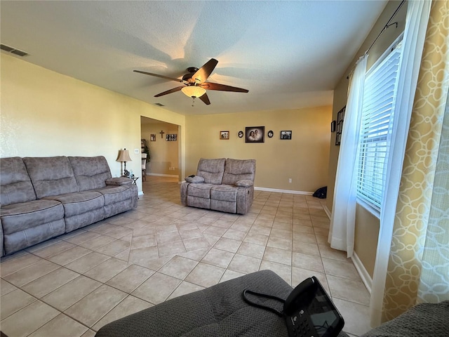 living room with light tile patterned flooring, ceiling fan, and a textured ceiling