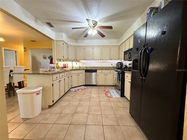 kitchen with sink, black appliances, kitchen peninsula, light tile patterned flooring, and cream cabinetry