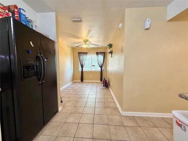 kitchen featuring light tile patterned floors, a textured ceiling, ceiling fan, and black fridge