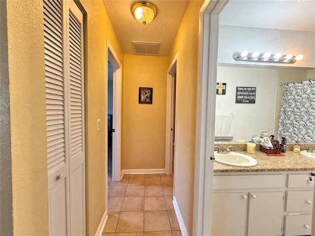 interior space with sink, a textured ceiling, and light tile patterned floors