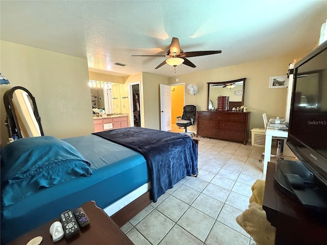 tiled bedroom with ceiling fan, connected bathroom, and a textured ceiling