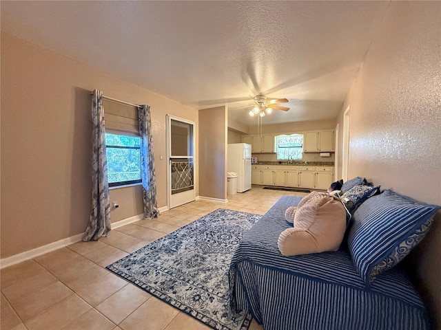 tiled bedroom with white refrigerator, ceiling fan, sink, and a textured ceiling