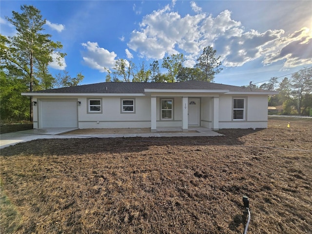 ranch-style home with a porch, concrete driveway, stucco siding, and an attached garage
