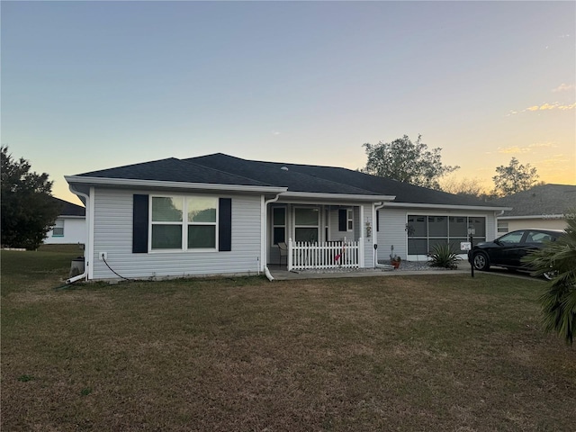 ranch-style home featuring covered porch and a lawn