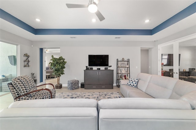 living room featuring hardwood / wood-style floors, a tray ceiling, and ceiling fan